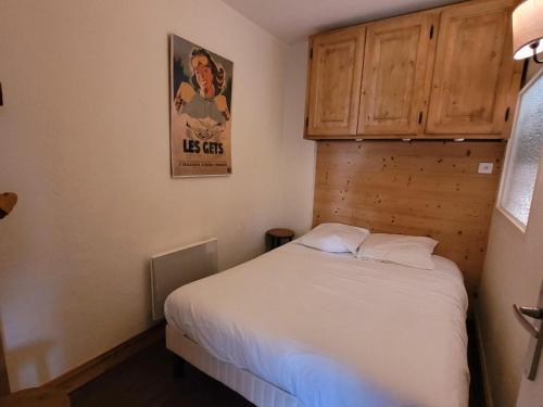 - une petite chambre avec un lit blanc et des placards en bois dans l'établissement Appartement rénové centre station, 3 étoiles, 4 pers, balcon, parking, Wi-Fi - FR-1-598-44, aux Gets