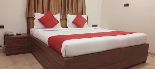 a bedroom with a large bed with red and white pillows at Shine Hospitality Palace in Mumbai