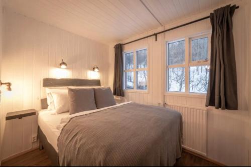 a bedroom with a large bed and two windows at Traditional Cottage with Jacuzzi and Lake View Laugarvatn, Árnessýsla, Islandia in Laugarvatn