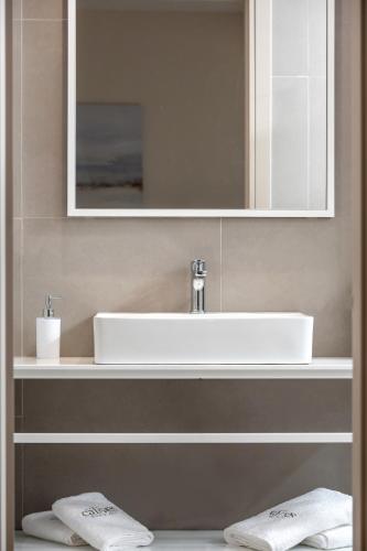 a bathroom with a white sink and a mirror at Calives Premium Stay in Kalyves Poligirou