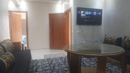 Cette chambre dispose d'une table et d'une télévision murale. dans l'établissement Appartement balnéaire Plage Sablette Mohammedia, à Pont Blondin