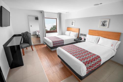 sypialnia z 2 łóżkami, biurkiem i krzesłem w obiekcie Six Hotel Guadalajara Expiatorio w mieście Guadalajara