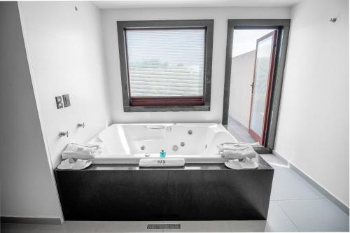 a bathroom with a large bath tub with a window at Six Hotel Guadalajara Expiatorio in Guadalajara