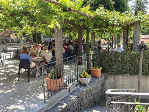 a group of people sitting at tables in a garden at Hotel Ristorante Grotto Serta in Lamone