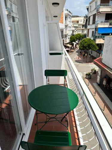 a green table and a chair on a balcony at L'Illa Hotel in Tossa de Mar