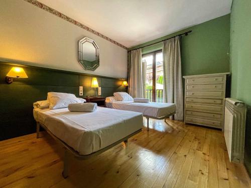 two beds in a room with green walls and wooden floors at Casa Elegancia Pleta de Saga in Ger