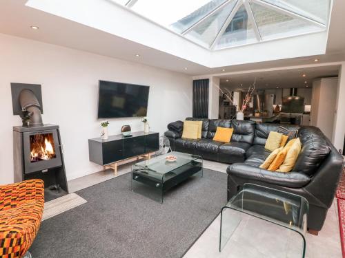 a living room with a black leather couch and a fireplace at Carr House Farm in Glossop