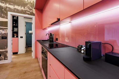 a kitchen with pink walls and a black counter top at Rosetti One in Constanţa