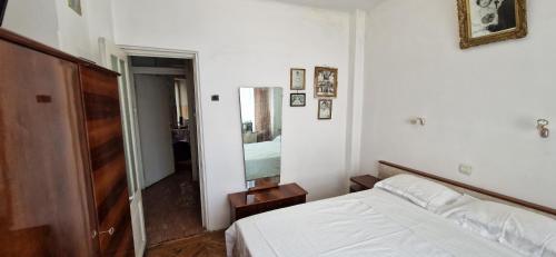 Schlafzimmer mit einem weißen Bett und einem Spiegel in der Unterkunft Domum - The Comunist Apartment in Bukarest