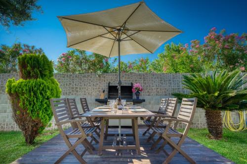 a table and chairs with an umbrella on a patio at Villa Angela in Ágios Matthaíos