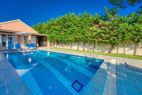 a swimming pool with blue chairs and trees at Villa Angela in Ágios Matthaíos
