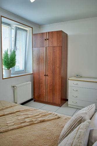 a bedroom with a wooden cabinet next to a bed at Vacation home Lubov in Kamianets-Podilskyi