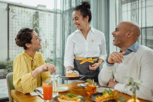 a woman and two people sitting at a table at voco Brussels City North by IHG in Vilvoorde