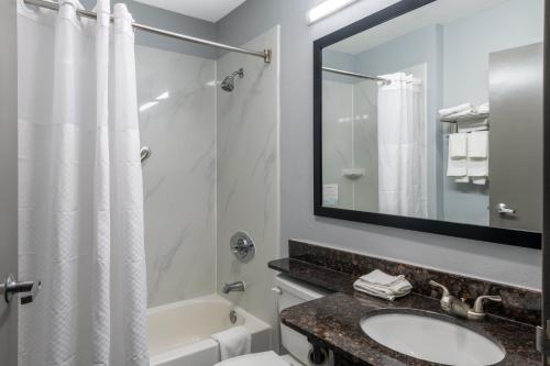 a bathroom with a sink and a tub and a mirror at Microtel Inn by Wyndham Spartanburg Duncan in Duncan