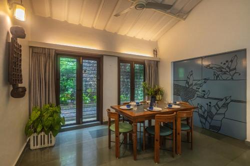 a dining room with a wooden table and chairs at SaffronStays Artica - 2 BDR cottage near Fariyas in Lonavala in Lonavala