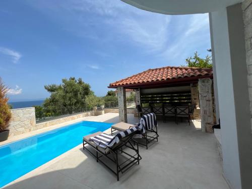 een patio met stoelen en een prieel naast een zwembad bij Sunny Seaside Villa-90 m from beach in Kriopigi