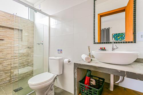 La salle de bains est pourvue d'un lavabo, de toilettes et d'un miroir. dans l'établissement Flats das Palmeiras, à Florianópolis