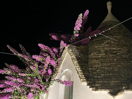 a bunch of purple flowers on a white wall at Trulli Harmonia con piscina - Alberobello in Alberobello