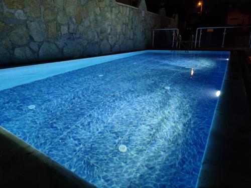 a large swimming pool with blue water at night at Soleil Hotel in Kuşadası