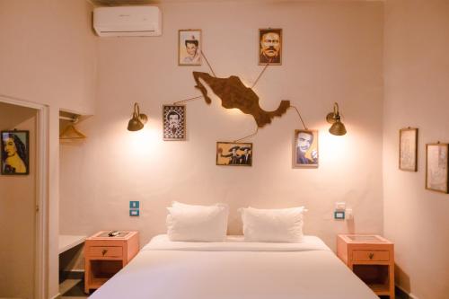 a bedroom with a white bed and pictures on the wall at Hotel Del Portal San Miguel de Allende in San Miguel de Allende