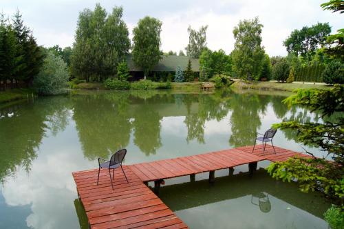 two chairs sitting on a dock in a pond at Złota Rybka in Glinojeck