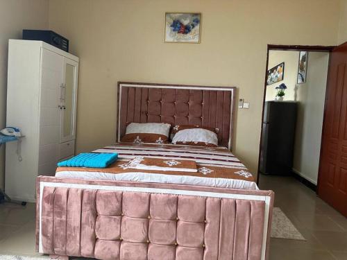 - un grand lit dans une chambre avec un cadre rose dans l'établissement Oak Cottage, à Dar es Salaam