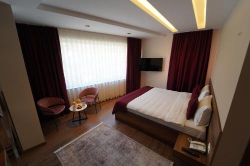 Habitación de hotel con cama, mesa y sillas en Monarch Hotel en Prizren