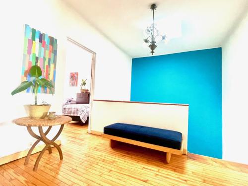 a room with a blue wall and a bench and a table at Indigo Guest House in Mexico City