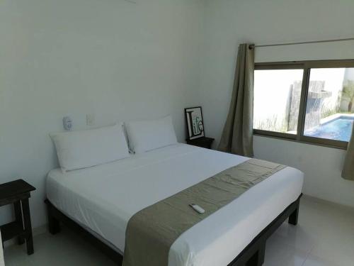 - un lit blanc dans une chambre avec fenêtre dans l'établissement VillaGera ¡Tu casa en la playa!, à Ursulo Galván