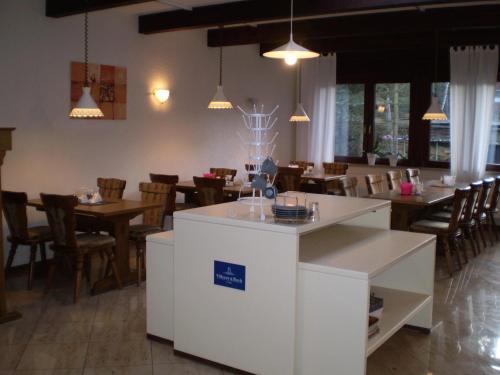 a dining room with tables and chairs and a counter at Hotel am Weißdornbusch in Gifhorn