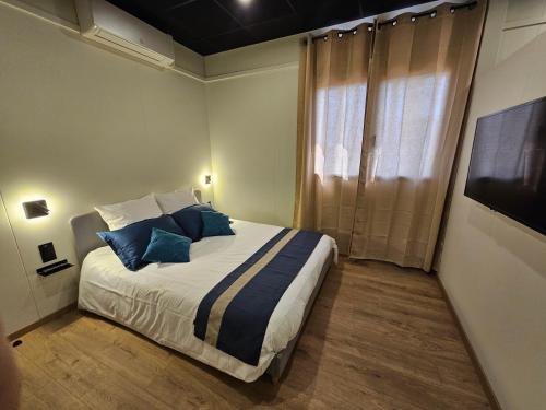 a bedroom with a bed with blue pillows and a television at Aérogites Chambley in Dommartin-la-Chapelle