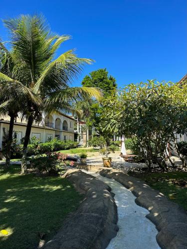 a yard with palm trees and a building at Pousada Corsario Buzios in Búzios