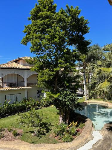 a tree in front of a house with a swimming pool at Pousada Corsario Buzios in Búzios