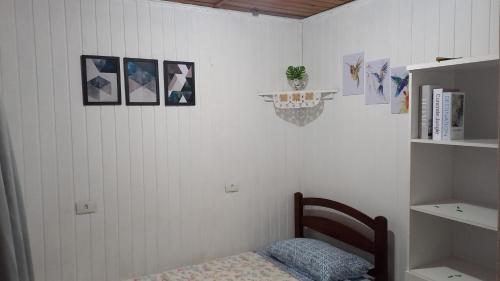 a room with a bed and a shelf with pictures on the wall at Casa Recanto in Campos do Jordão