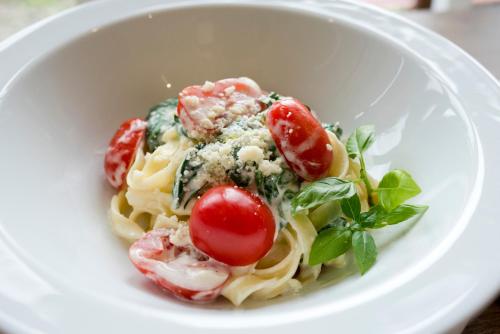 a white bowl filled with pasta with tomatoes and spinach at Pensjonat pod Samowarem in Tylicz