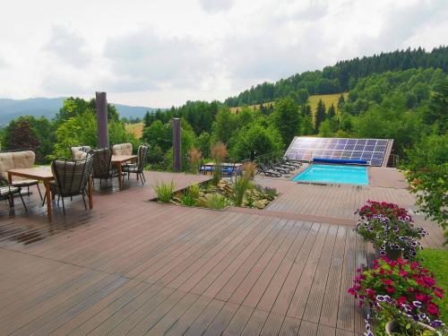 a deck with a table and chairs and a swimming pool at Pensjonat pod Samowarem in Tylicz