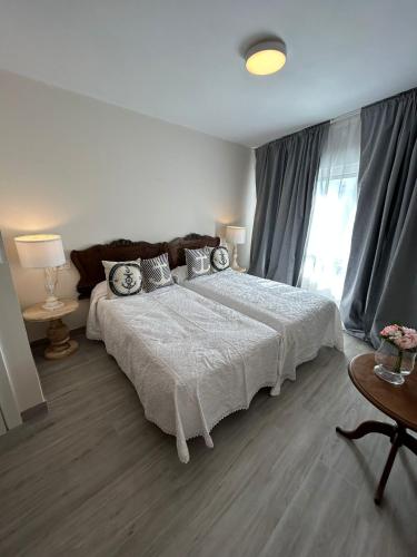 a bedroom with a large white bed and a window at LA CASA DEL MUELLE in Avilés