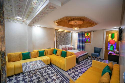 a living room with a yellow couch and a bed at Hotel & Ryad DALILA in Fès