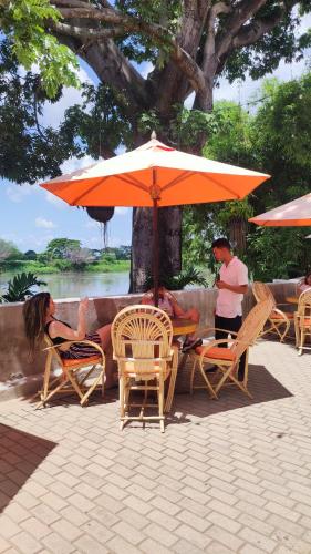 a group of people sitting in chairs under an umbrella at HOTEL NIETO MOMPOX, ubicado en el corazón del centro histórico, frente al rio magdalena en zona de malecón in Mompos