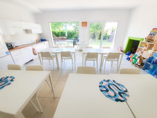 a kitchen with white tables and chairs in a room at Villa Łeba Pokoje & Apartamenty in Łeba