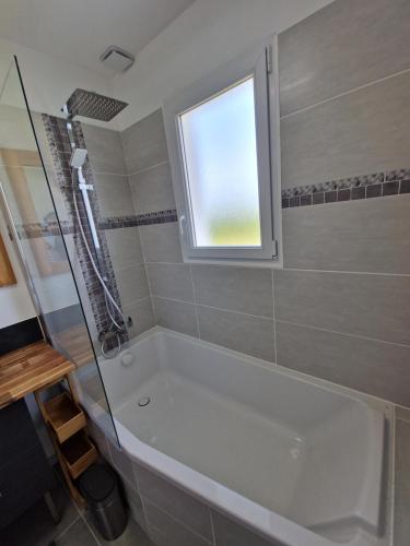 uma casa de banho com uma banheira e uma janela em La VILLA DES PINS Maison Standing 7 pers Terre et Mer em Brach