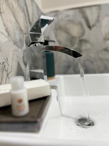 a faucet pouring water into a glass on a sink at Akropoli Exclusive Room in Agrigento
