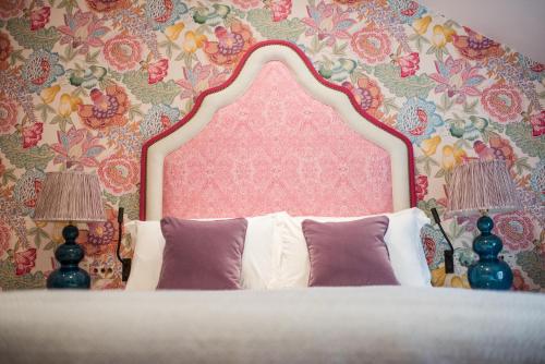 a bedroom with a bed with a pink headboard and two lamps at Dewars Restaurant and Rooms in Malton