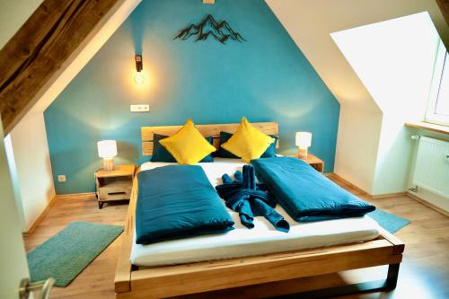 a bedroom with a bed with blue sheets and yellow pillows at Ferienhaus Bergauszeit in der alten Post in Nesselwang