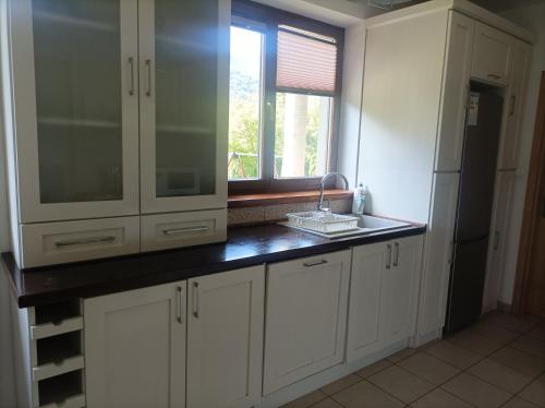 a kitchen with white cabinets and a sink and a window at Domek Nad Dunajcem Liptak in Tylmanowa