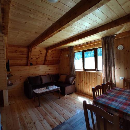 salon w drewnianym domku z kanapą i stołem w obiekcie Wooden cottage Podgora w mieście Žabljak