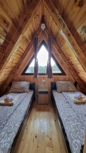 dwa łóżka w drewnianym domku z oknem w obiekcie Wooden cottage Podgora w mieście Žabljak