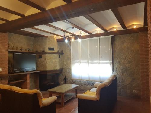 ein Wohnzimmer mit einem Kamin und einem TV in der Unterkunft CASA RURAL CURTIDORES in El Batán