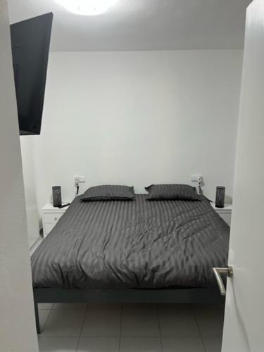 a bed in a white room with a black comforter at moriones in Torrevieja