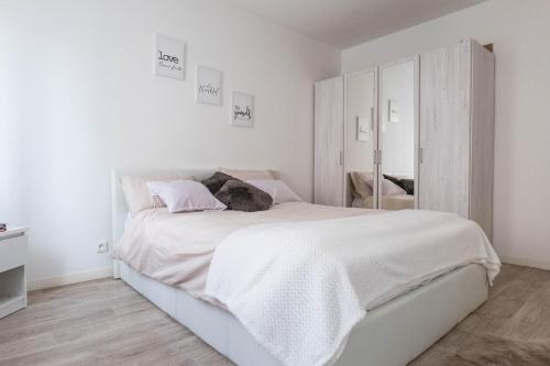 a white bedroom with a large bed with white sheets at Golden Location in Bagnolet
